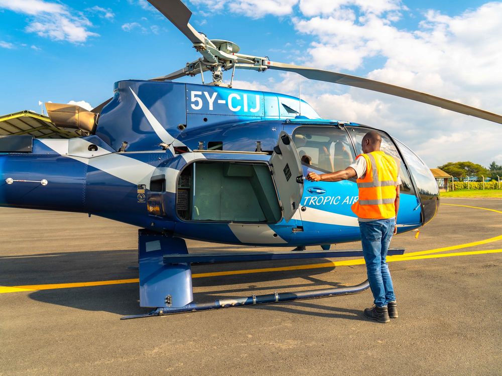 Ground crew opening the cabin door for a passenger on the tarmac under a bright blue sky
