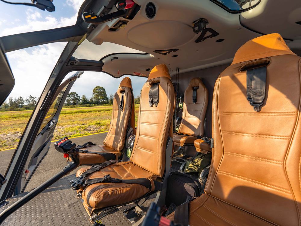 Tropic Air helicopter cabin at golden hour, door open on the airfield