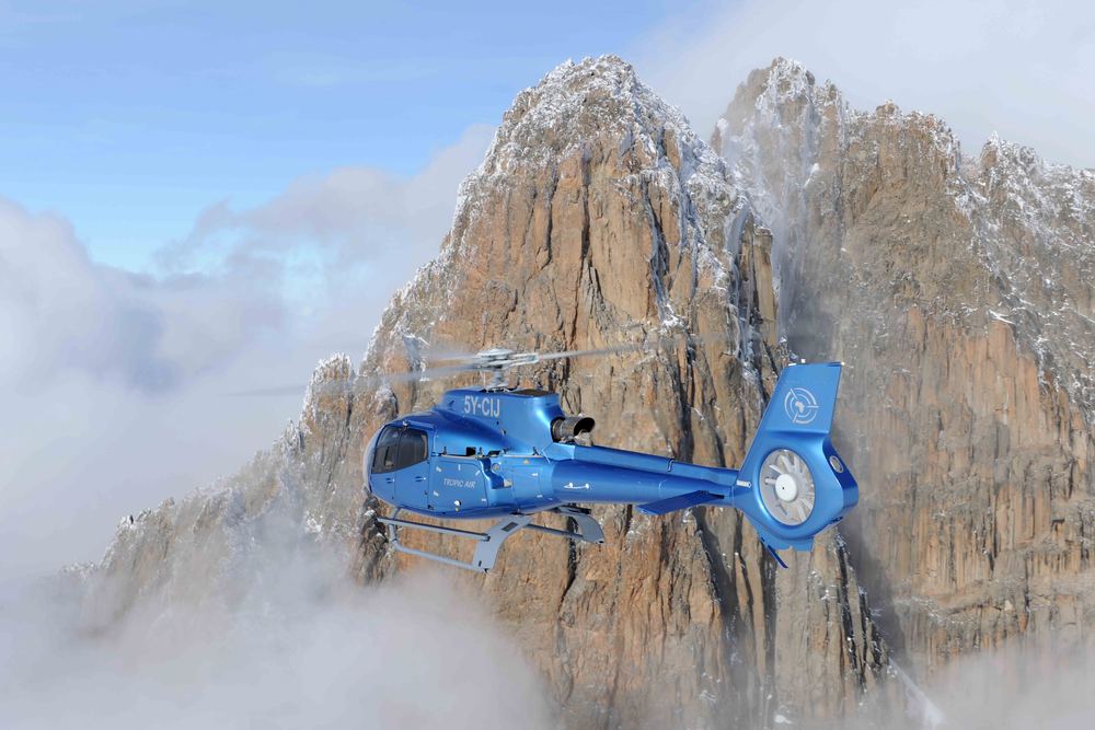 Tropic Air helicopter banking past a rugged highland peak