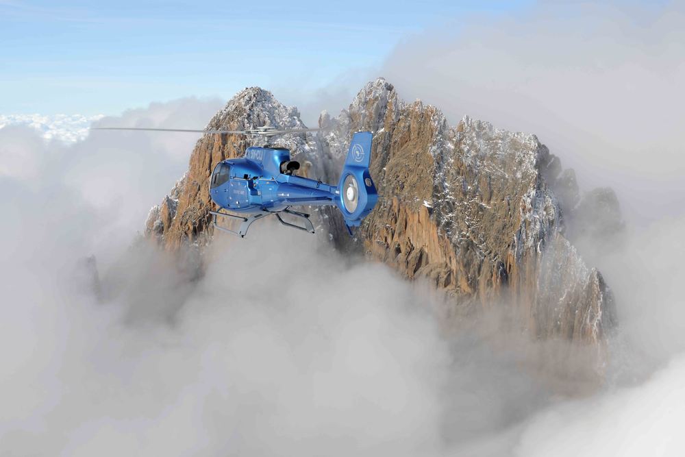 Two Tropic Air helicopters flying alongside each other over Kenya's highlands